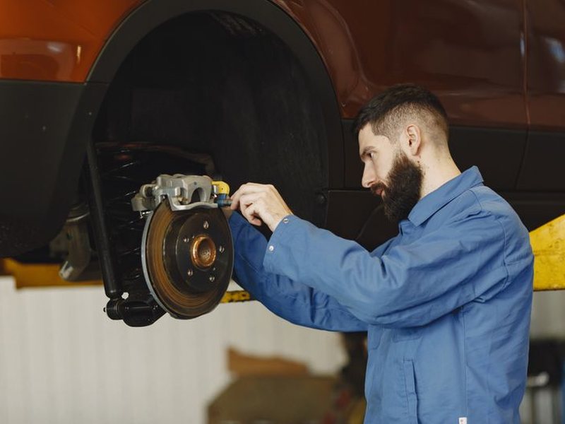 Technician servicing a brake rotor on a lifted vehicle