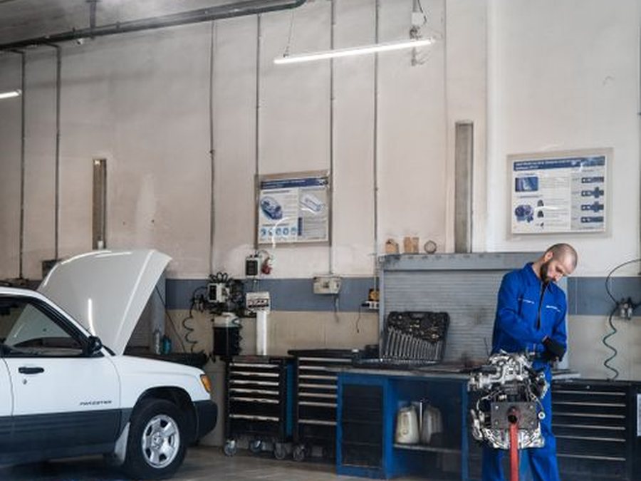 Technician working beside an engine on a stand inside the service bay