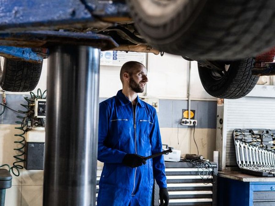 Technician beside a car raised on a lift in the repair bay